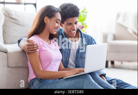 Jeune couple apprécie le temps de qualité ensemble tout en utilisant un ordinateur portable à la maison Banque D'Images