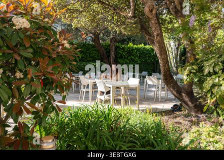 Terrasse de jardin à Antibes avec femme assise à table blanche Banque D'Images