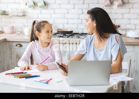 Mère et fille appréciant le temps créatif ensemble à une table de cuisine dans l'après-midi Banque D'Images