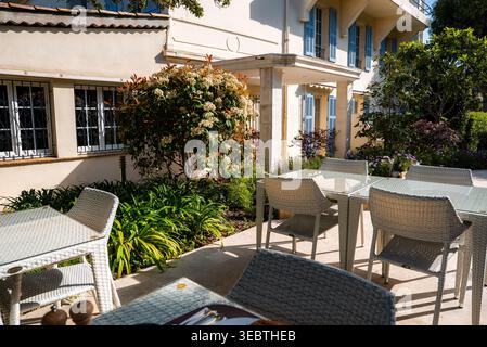 Patio salle à manger à côté d'une villa crème avec volets bleus à Antibes Banque D'Images