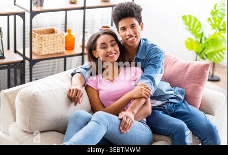 Couple profite d'un moment confortable ensemble sur un canapé élégant dans un salon lumineux Banque D'Images