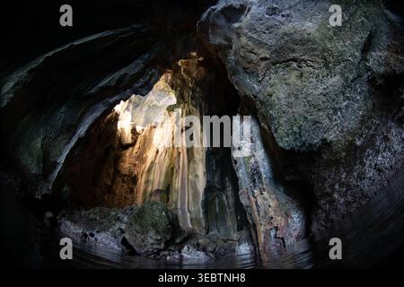 La lumière du soleil tombe à travers une lucarne dans la grotte de la cathédrale située sur l'île de Pinisil, aux Philippines. Cette merveille géologique est une attraction touristique célèbre. Banque D'Images
