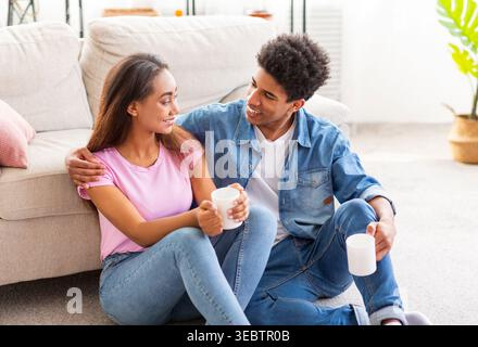 Couple profitant d'un moment confortable ensemble tout en étant assis sur le sol dans un salon élégant Banque D'Images
