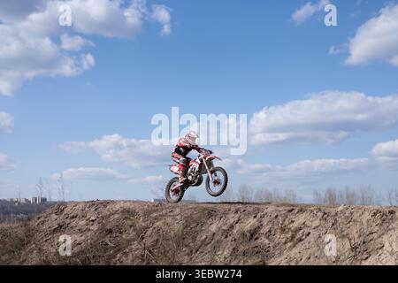 Kharkov Ukraine en mars 2021 les cavaliers pratiquent le motocross sur des vélos enduro sur une piste hors route le ciel est clair avec quelques nuages visibles. Banque D'Images