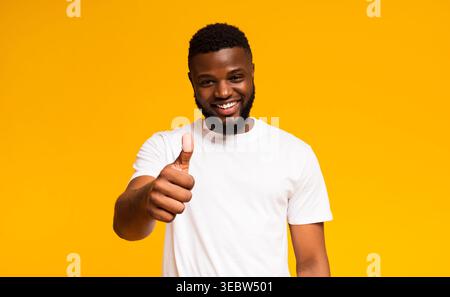 L'homme souriant donne Thumbs sur un fond jaune vif Banque D'Images