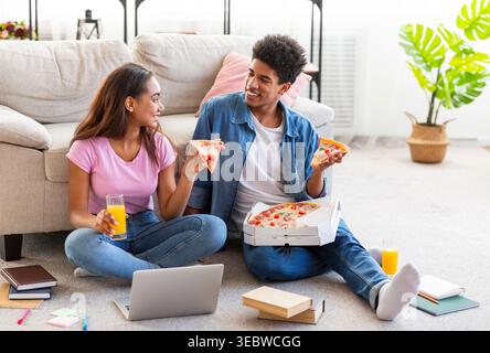 Profiter de pizzas et de boissons tout en étudiant ensemble dans un salon confortable Banque D'Images