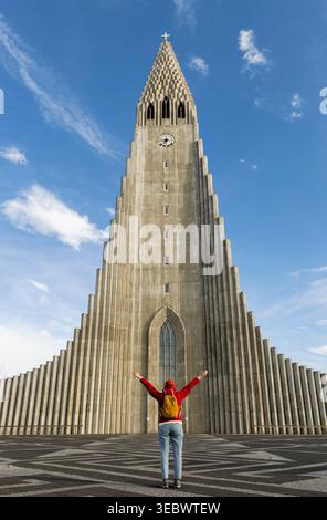 Femme Backpacker debout et regardant l'église paroissiale luthérienne Hallgrimskirkja est la plus grande église dans le centre de Reykjavik, en Islande Banque D'Images