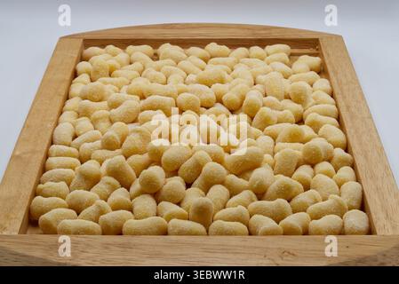 Gnocchi de pommes de terre crues fraîches saupoudrées de farine et disposées sur un plateau en bois pour la cuisson. Banque D'Images