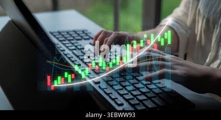 Une vue rapprochée des mains tapant sur un clavier d'ordinateur portable avec une superposition de graphique financier, représentant l'analyse de données et la négociation dans un professionnel Banque D'Images