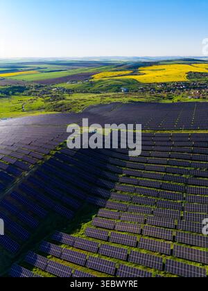 Les panneaux solaires couvrent une vaste zone dans la campagne sous un ciel lumineux. Les champs s'étendent au loin, créant une scène de production d'énergie in natur Banque D'Images