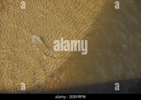 La lumière joue à la surface d'une rivière calme, créant de beaux motifs tandis que de douces ondulations se déplacent à travers l'eau. La scène capture un moment paisible Banque D'Images