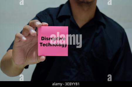 Homme d'affaires tient dans les mains une carte avec le nom de la technologie disruptive. Banque D'Images