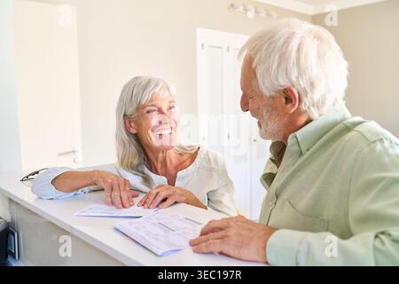Planification de la retraite et sécurité financière — un couple de personnes âgées heureux examine des documents importants ensemble à la maison. Banque D'Images