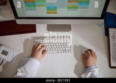 Médecin travaillant sur l'ordinateur avec le programme du patient dans le cabinet médical Banque D'Images