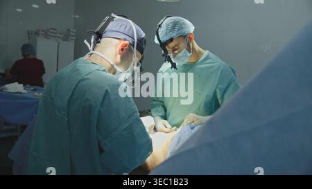 Équipe clinique deux hommes médecins chirurgiens traitant la chirurgie cardiaque opération chirurgicale thérapeutes hommes avec scalpel coupe médecine d'urgence Banque D'Images