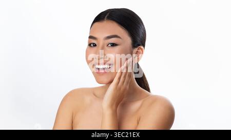 Femme souriante présentant la routine de soins de la peau dans la lumière naturelle Banque D'Images