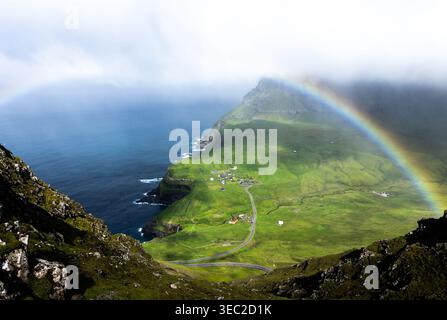 Une vue aérienne ensoleillée de Gasadulur dans les îles Féroé, ornée d'un arc-en-ciel. Banque D'Images