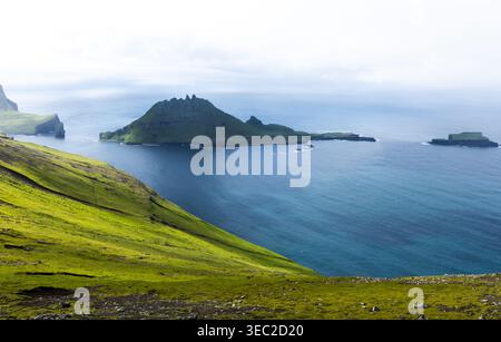 Vue panoramique sur l'île de Tindholmur. Des prairies verdoyantes et la mer bleu profond créent un beau contraste. Îles Féroé Banque D'Images