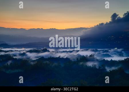Un lever de soleil d'été à couper le souffle sur le paysage montagneux de Zuozhen à Tainan, Taiwan, avec des nuages bas et des sommets montagneux lointains. Banque D'Images