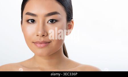 Jeune femme à la peau lisse posant sur un fond clair dans un look simple mais élégant Banque D'Images