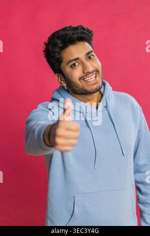 J'aime. L'homme indien lève les pouces est d'accord avec quelque chose ou donne une réponse positive recommande la publicité aime les bons commentaires d'idée, célébrant la victoire de succès. Guy isolé sur fond rouge studio Banque D'Images