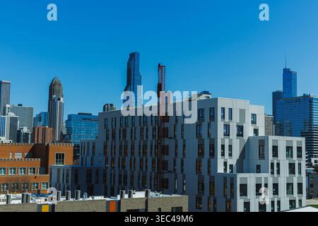 De grands bâtiments s'élèvent dans le centre-ville de Chicago par temps clair. Un chantier de construction est visible près du bord de la vue. La skyline montre différents architectu Banque D'Images