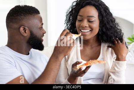 Couple appréciant Pizza ensemble dans un salon confortable lors d'une soirée de détente Banque D'Images