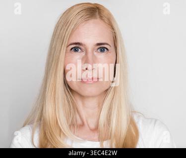 Portrait d'une femme avec de longs cheveux blonds et des yeux bleus sur un fond Uni Banque D'Images
