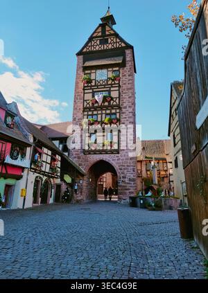 Pittoresque rue médiévale avec la tour Dolder et des maisons colorées à colombages à Riquewihr, Alsace, France. Banque D'Images