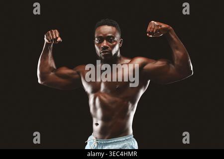 Strong Man fléchit les muscles en mettant en valeur Fitness et force dans Studio Lighting Setup Banque D'Images
