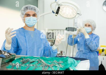 Jeune vétérinaire en tenue chirurgicale debout en salle d'opération vétérinaire Banque D'Images