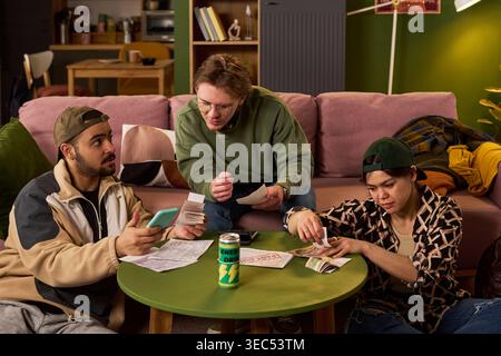 Jeunes adultes multiethniques examinant les factures, comptant l'argent, vérifiant le smartphone, planifiant le budget partagé à la maison. Utile pour les finances des étudiants, les dépenses de colocation, le coût de la vie thèmes Banque D'Images
