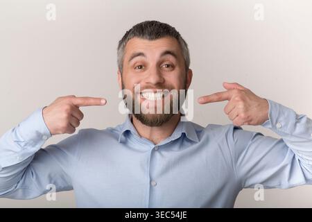 L'homme montre un sourire lumineux avec Thumbs Up tout en portant une chemise bleu clair à l'intérieur Banque D'Images