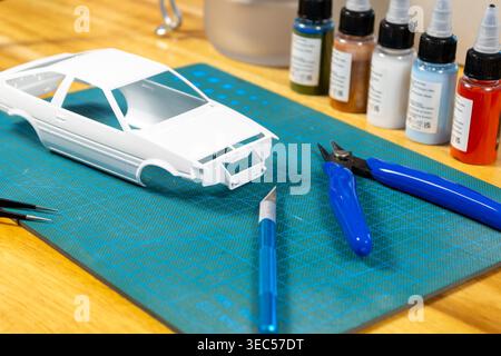 Gros plan du kit de voiture modèle non peint avec outils et peinture sur tapis de coupe – espace de travail de modélisation de l'échelle Banque D'Images