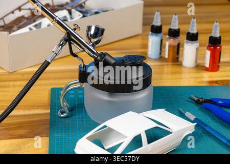 Gros plan du kit de voiture modèle non peint avec outils et peinture sur tapis de coupe – espace de travail de modélisation de l'échelle Banque D'Images