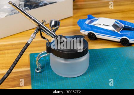 Gros plan du kit de voiture modèle non peint avec outils et peinture sur tapis de coupe – espace de travail de modélisation de l'échelle Banque D'Images