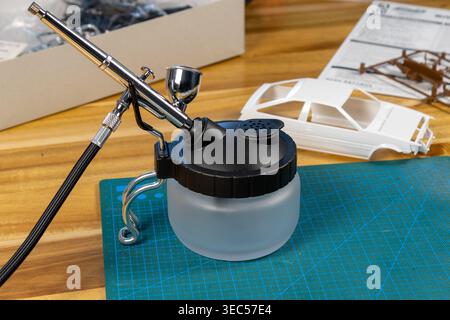 Gros plan du kit de voiture modèle non peint avec outils et peinture sur tapis de coupe – espace de travail de modélisation de l'échelle Banque D'Images