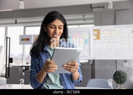 Femme travaillant sur tablette numérique, se tient dans une salle de réunion moderne Banque D'Images
