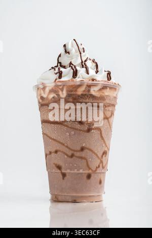 Milkshake au chocolat servi dans un verre clair sur fond blanc. Boisson isolée Banque D'Images