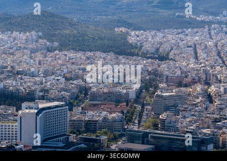 Image du quartier d'Ilisia à Athènes, avec l'emblématique bâtiment Hilton Athens au premier plan et l'étalement urbain dense Banque D'Images