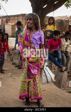 Portrait d'une femme indienne âgée portant un sari traditionnel lumineux, debout à l'extérieur dans un village du Bihar, en Inde elle offre un sm chaleureux et authentique Banque D'Images