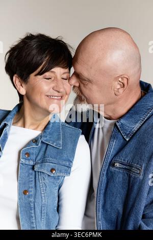 Un couple âgé joyeux partage un baiser tendre, rayonnant d'amour et de connexion. Banque D'Images