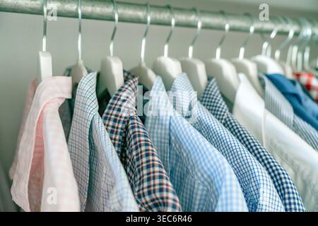 Gros plan de chemises sur des cintres montrant des textures et des motifs de tissu. Concept d'organisation de la mode et de la garde-robe. Banque D'Images