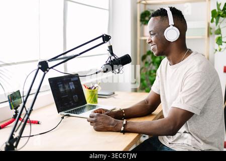 Jeune homme africain enregistrant un podcast tout en diffusant en direct sur le téléphone au home studio Banque D'Images