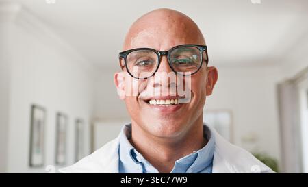 Portrait de médecin masculin souriant dans la clinique portant des lunettes et un manteau blanc, professionnel de la santé Banque D'Images