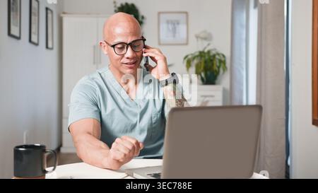 Professionnel de santé masculin au téléphone pendant la consultation vidéo de télémédecine au bureau à domicile Banque D'Images