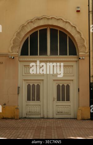 Porte historique décorative à Subotica, Serbie avec une élégante arche et une façade pastel douce. Détail architectural dans la vieille ville. Banque D'Images