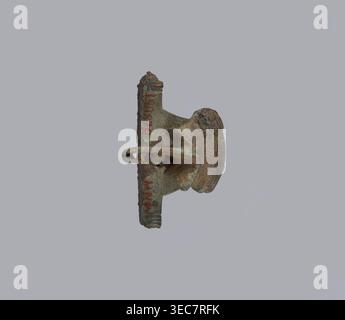 Broche avec barre transversale. Broche avec un noeud fait d'une large bande légèrement incurvée décorée de lignes gravées, avec une barre transversale lisse à la transition vers une grande gaine. À la base de la broche, la bande se termine par une traverse épaisse, cylindrique et lisse. Condition : broche manquante, copeaux sur la paroi supérieure de la gaine. Lieu d'origine : Prusse . Broche ; hauteur 4 cm, largeur 4,6 cm., un objet métallique vieilli suspendu sur un fond gris clair Uni, montrant une surface corrodée et irrégulière avec des textures rugueuses et des zones piquées ; l'objet affiche une patine verdâtre et des tons de rouille brun, avec plus foncé Banque D'Images
