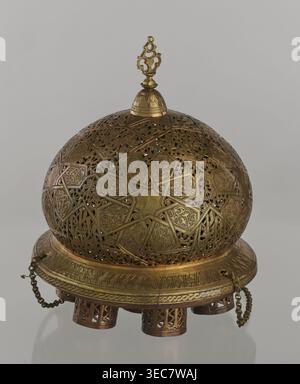 Lampe, créateur inconnu, art islamique, culture arabe ; lampe à huile en métal avec ornement géométrique et inscriptions arabes ; couvercle décoré d'un motif d'étoile ; base de disque avec sept trous pour les manchons en verre récipients d'huile en verre manquants. XIXe-XXe siècle, Damas, Syrie. Hauteur 40 cm ; diamètre 32 cm ; poids 2,4 kg., Un objet en métal arrondi et orné avec une section supérieure en treillis bombé et une base circulaire, principalement de couleur or et laiton avec des accents de bronze plus foncé ; le dôme présente des découpes géométriques et florales complexes avec un motif en forme d'étoile et des panneaux à motifs répétitifs, et une parenthèse décorative Banque D'Images