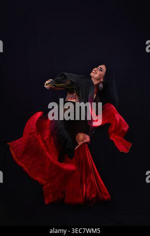Belle jeune femme en costume oriental rouge dansant avec des voiles éventail de soie agitant Banque D'Images